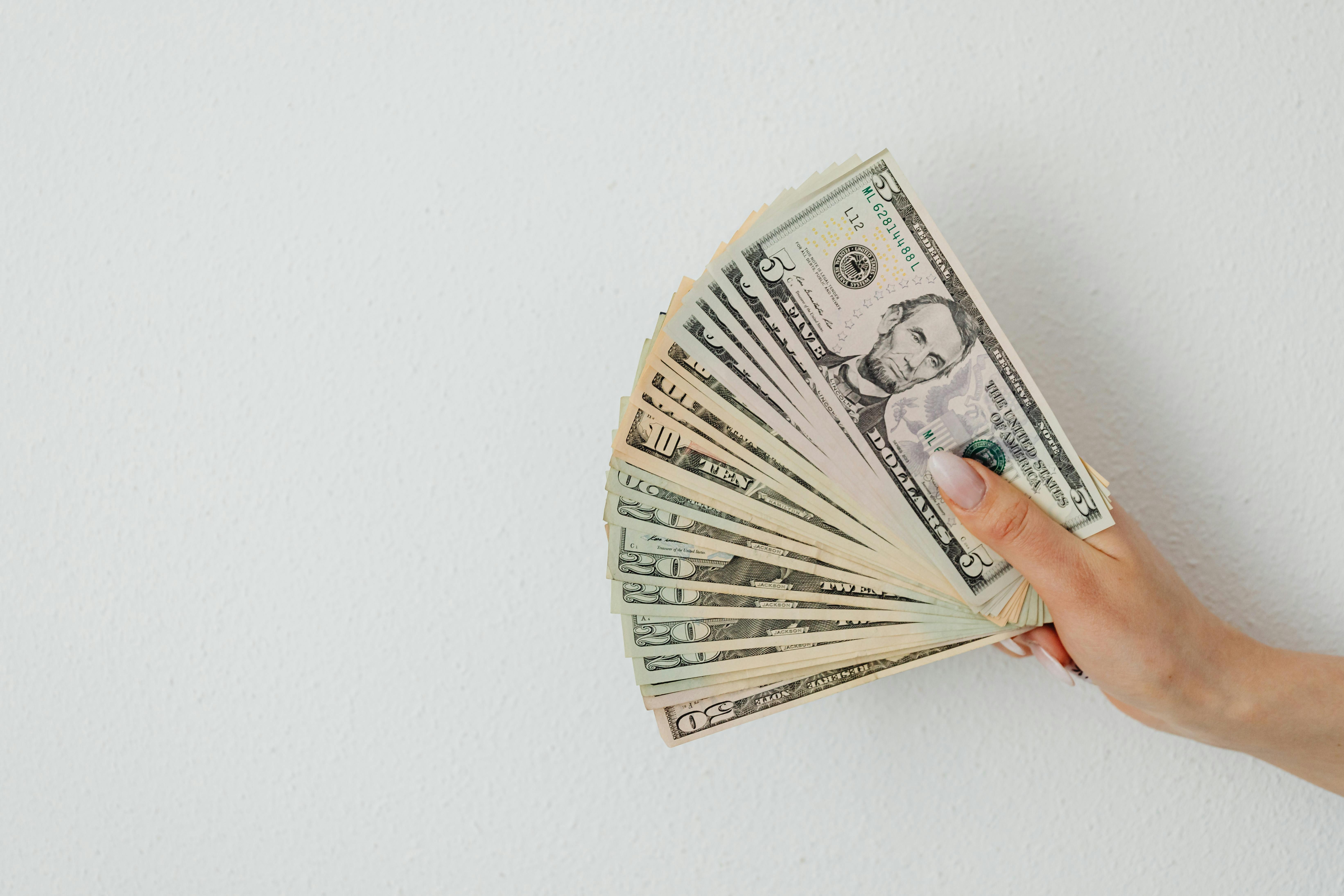A fan of fice-dollar-bills in a person's hand